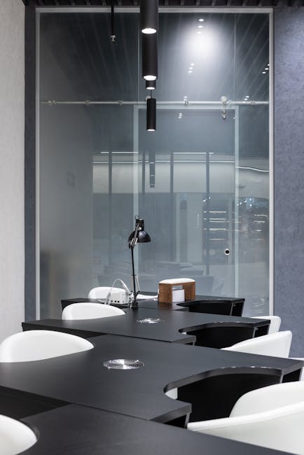Minimalist office interior with sleek black desks and modern lighting.