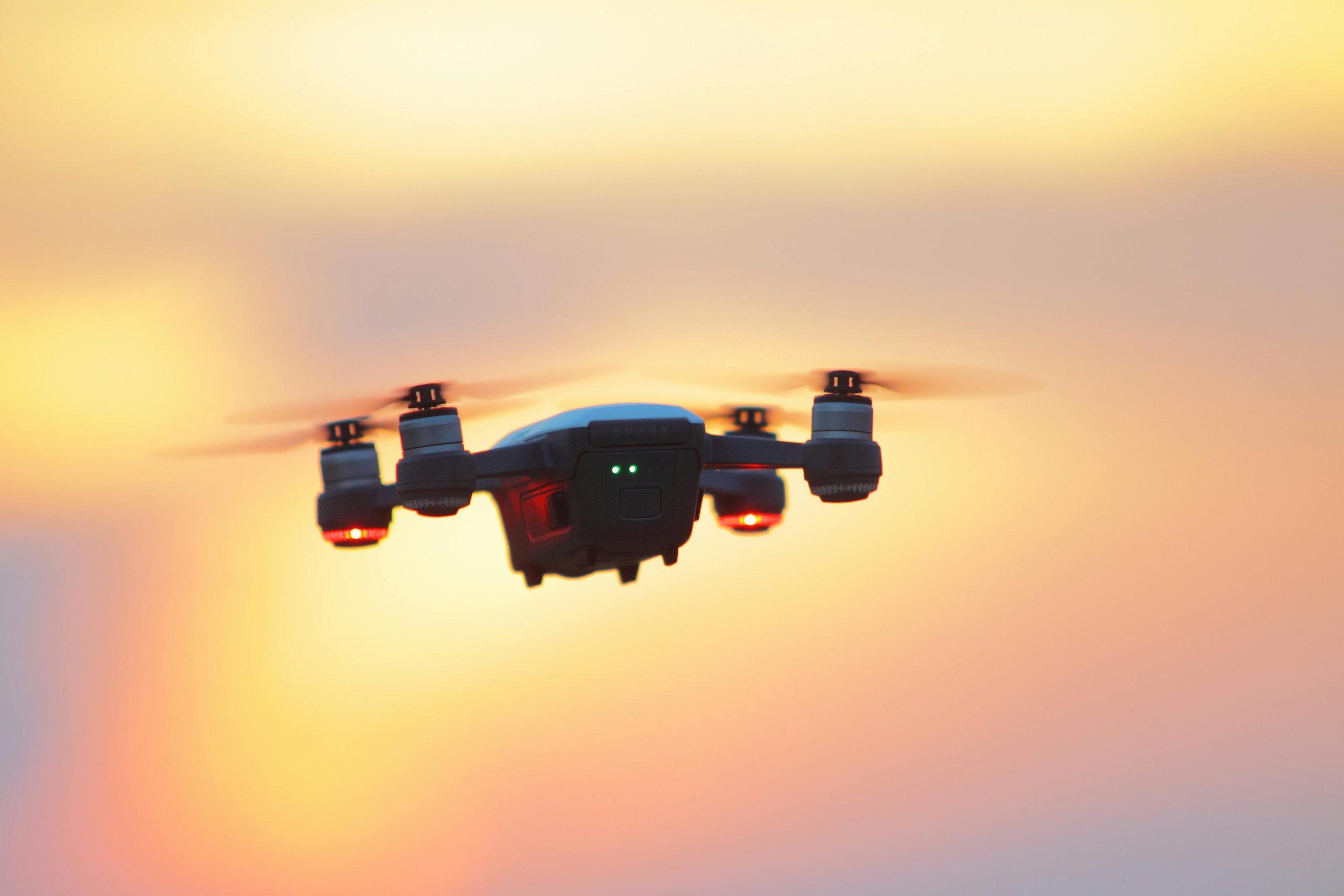 Aerial drone photography capturing a drone flying in a vibrant sunset sky.