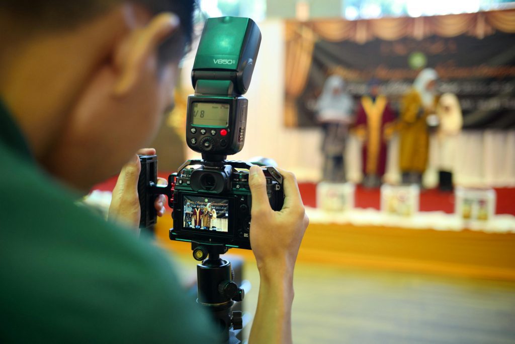 A photographer takes pictures at an event in Shah Alam, focusing on people on stage.