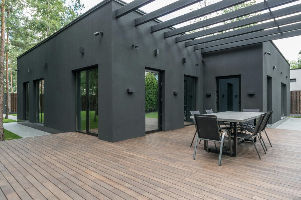 Contemporary black house with spacious wooden terrace and outdoor seating area.